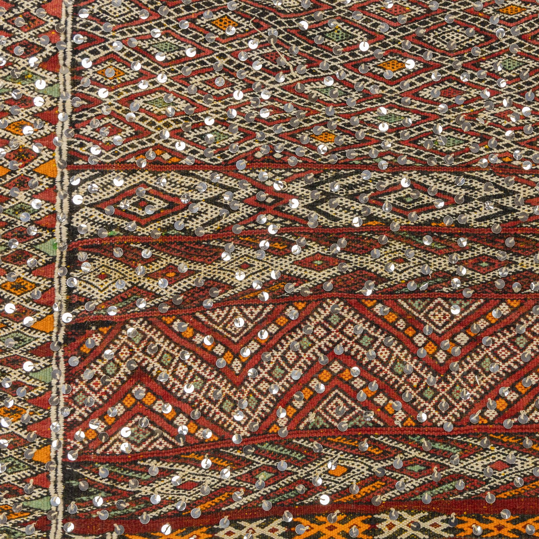Moroccan Berber kilim rug, flatwoven with bands of geometric lozenge and chevron motifs in red, orange, ivory and green, decorated with applied sequins, fringed ends