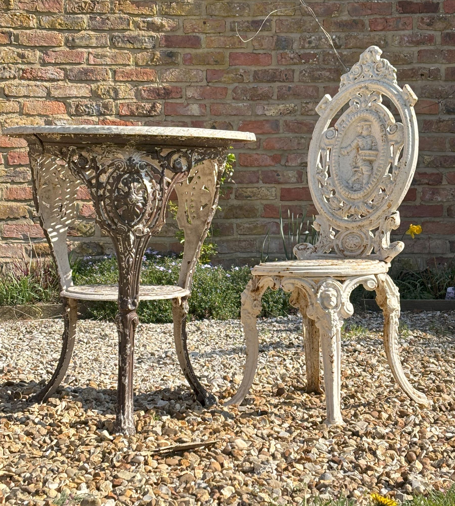 Victorian white painted cast iron garden chair, the figural cartouche back above an openwork seat, raised on cabriole supports (H96cm) together with a  cast iron garden table (H74cm, D62cm)  - COLLECTION BY APPOINTMENT FROM: The White House, Thirsk Road, Easingwold, York, YO61 3NF - CALL 01723 507111 TO ARRANGE