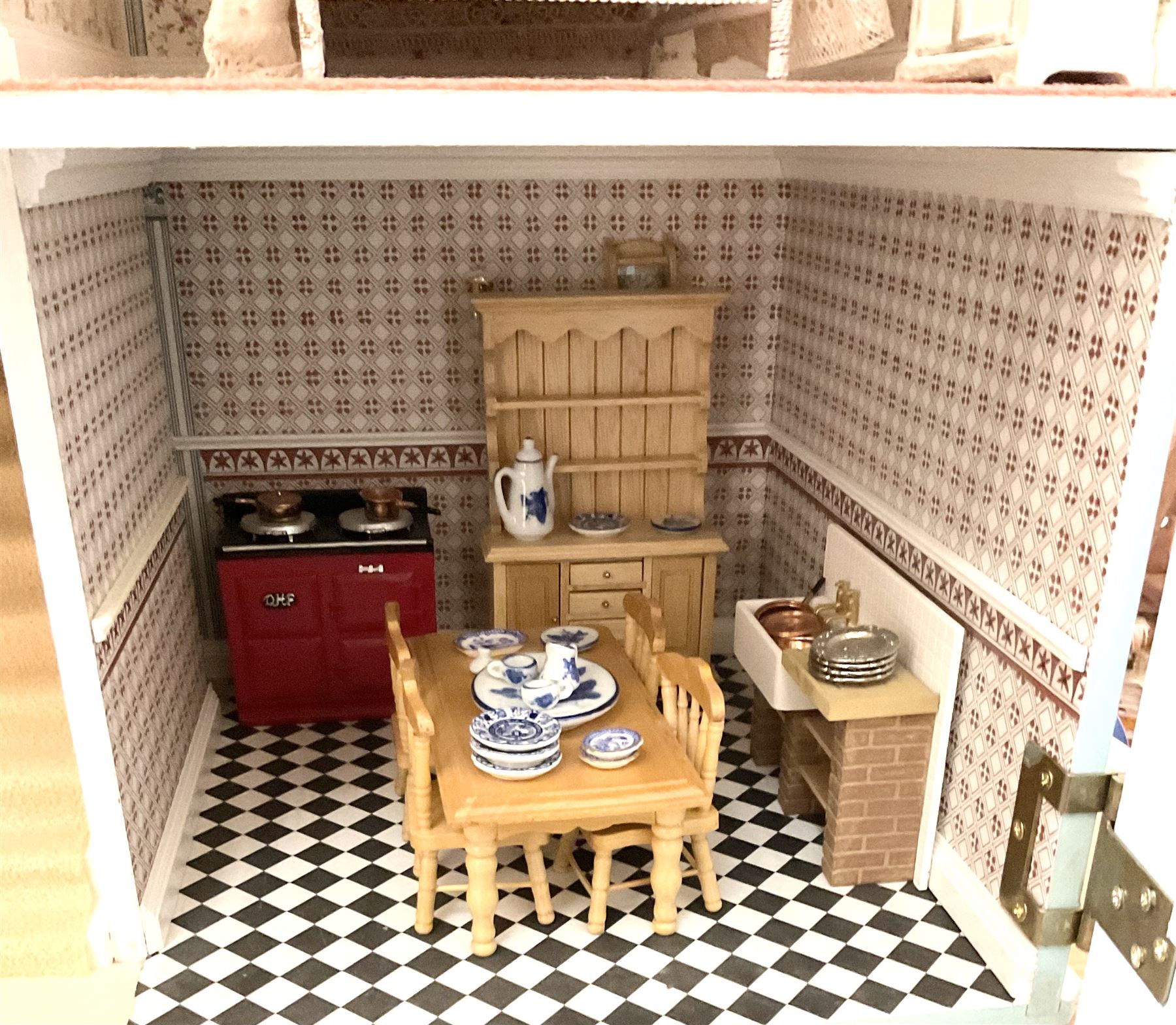 Georgian style wooden double fronted three-storey dolls house with pale blue stucco finish under a faux tiled roof with two chimney stacks, the double hinged front opening to reveal six fully decorated rooms with floor coverings, central staircase, porcelain fitted bathroom, kitchen with deep white sink and Aga cooker, electric lighting with adaptor, fully furnished with French style and other furniture, grand piano etc, and comprehensive range of accessories H82cm W61cm D31cm