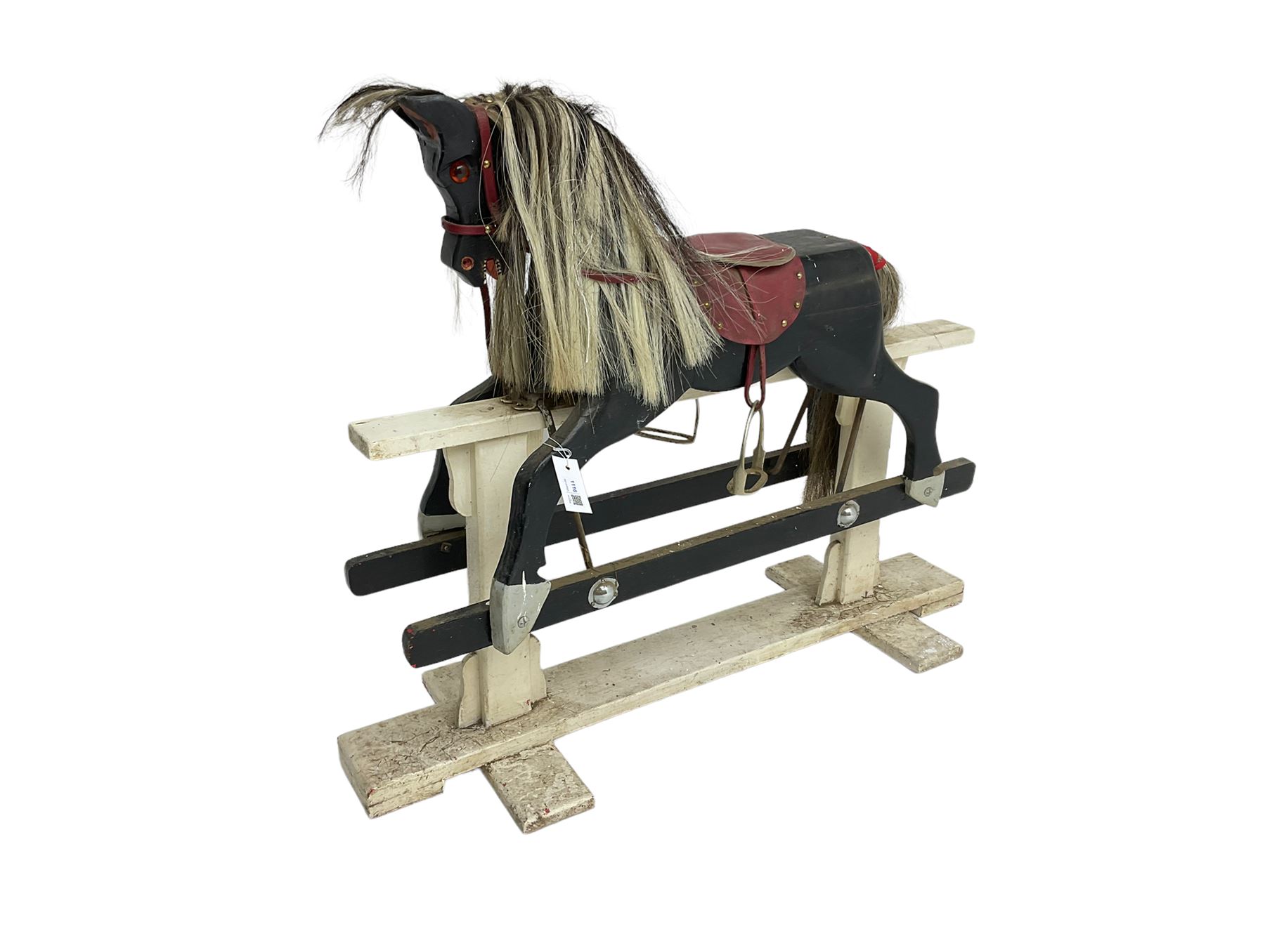 20th century black painted rocking horse on white painted trestle base, fitted with saddle and stirrups 