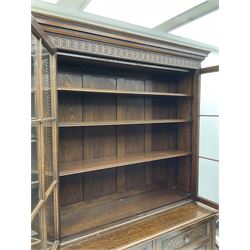 Waring and Gillow - oak bookcase on cupboard, projecting cornice over arcade frieze, guilloche upright decoration, the top section enclosed by three astragal glazed doors, the lower section enclosed by three geometric panelled doors with blind fretwork decoration, on turned feet