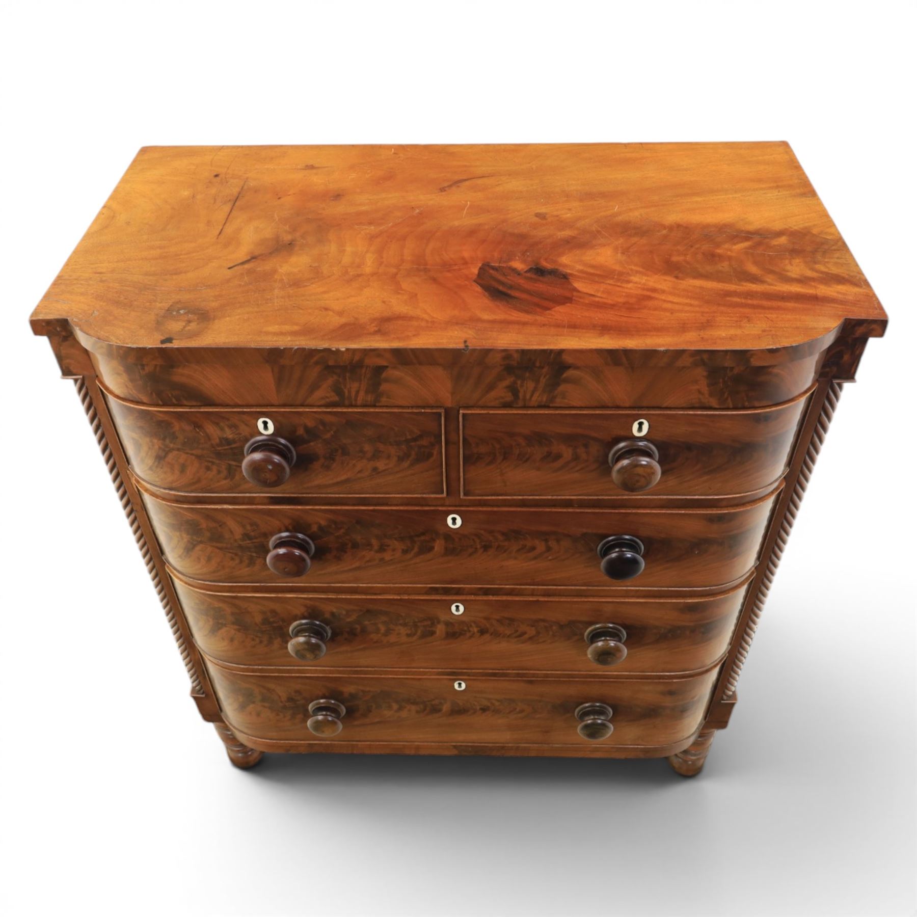 Victorian mahogany bow fronted chest, fitted with two short and three long drawers, flame mahogany front, bone escutcheons and turned wooden handles, quarter barley twist columns, raised on turned supports