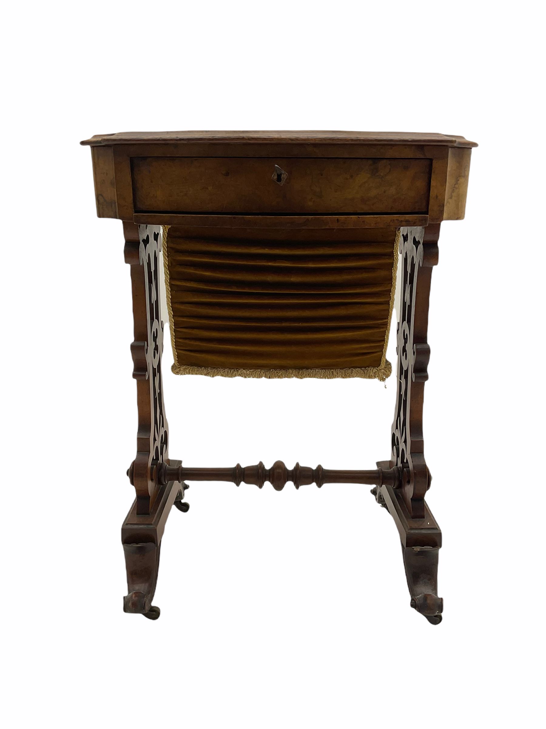 Victorian figured walnut work table, the shaped moulded top over single drawer and upholstered bag, shaped end supports with pierced decoration joined by turned stretcher, splay scroll carved supports