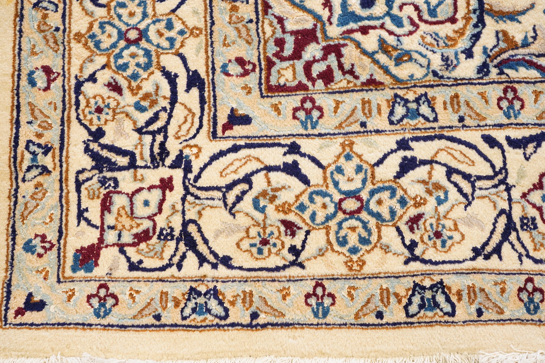 Persian Nain ivory ground rug, the busy oval field profusely decorated with scrolling foliate decoration and palmettes in citrine and indigo tones, the central medallion with matching spandrels, the multiple guard bands with repeating stylised quatrefoil motifs and trailing scrolling foliage and flowerheads