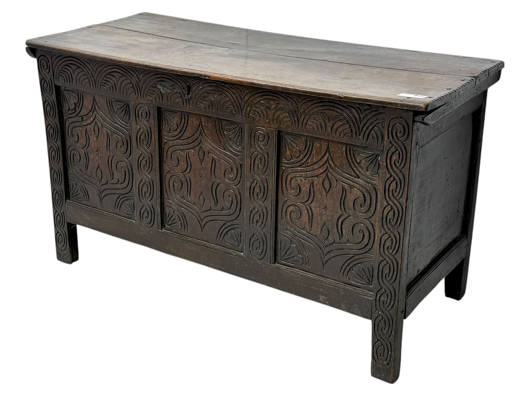 English carved oak coffer, hinged rectangular lid with indented side edges, internal candle-box, front with three-panel front with decorative carvings, raised on stile feet, circa 1700