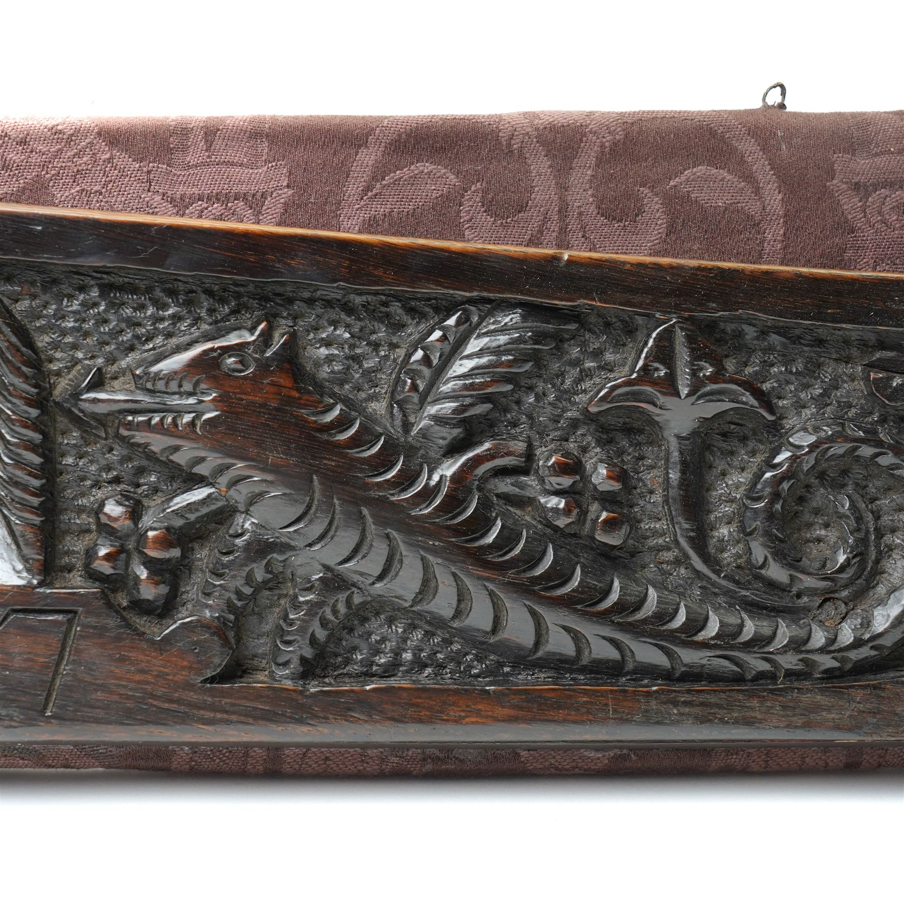 17th century walnut frieze, or pediment, carved with a smiling mans faced flanked my two creatures, incised date 1617, mounted on fabric panel, W52cm