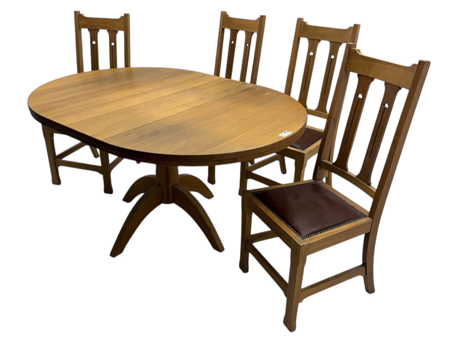 Contemporary light oak round extending dining table with four chairs, table has fold out leaf attached underneath on four out-swept legs, Oak chairs with straight top rail over twin slat back with pierced motifs, brown leather seat with brass studs, square legs joined by plain stretcher 
