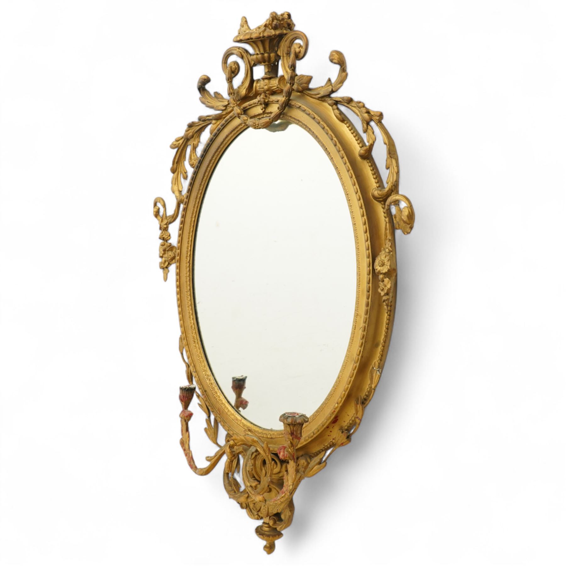 Late 19th century Louis XVI style giltwood and gesso girandole oval wall mirror, the oval frame surmounted with stylized urn finial and ribbon-tied garlands, laurel swags and rosettes, egg and dart decorated inner moulding and linked acorn outer moulding, flanked by intertwined foliate decorated candle branches 