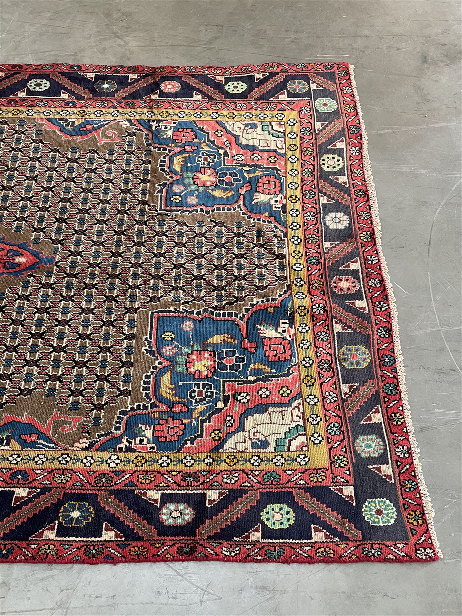 Persian Hamadan rug, the rosette pole medallion on a pale field decorated with stylised motifs, the blue band border decorated with stylised flower heads