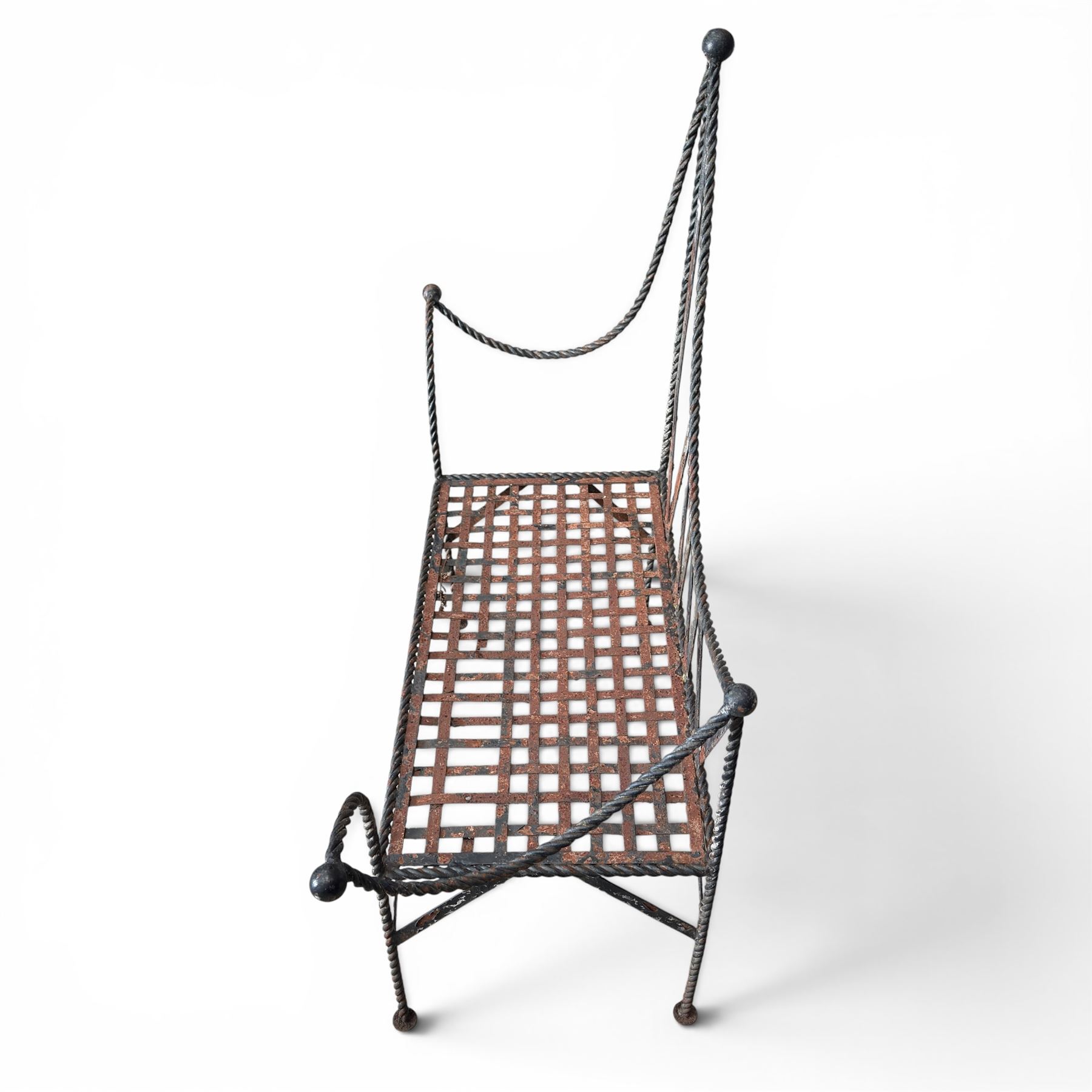Victorian design wrought iron garden bench, with asymmetrical rope-twist frame, arched back and sides over out-swept arm terminals with ball finials, flanking a lattice seat, in antique black-painted weathered finish