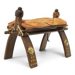 20th century Camel stool, with wooden turned finials, above a tooled leather seat, curved ...