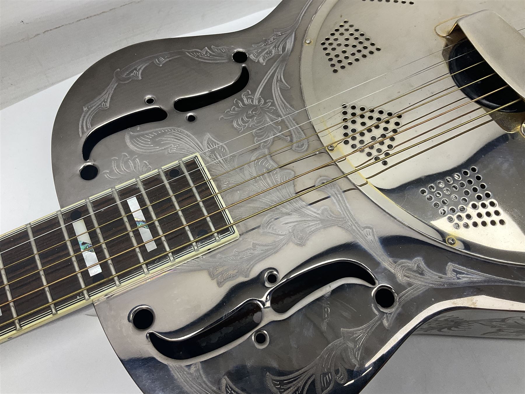 Ozark metal cased resonator guitar with all over chased foliate decoration to the polished finish and mother-of-pearl inlay to the fretboard L100cm; in Stagg hard carrying case