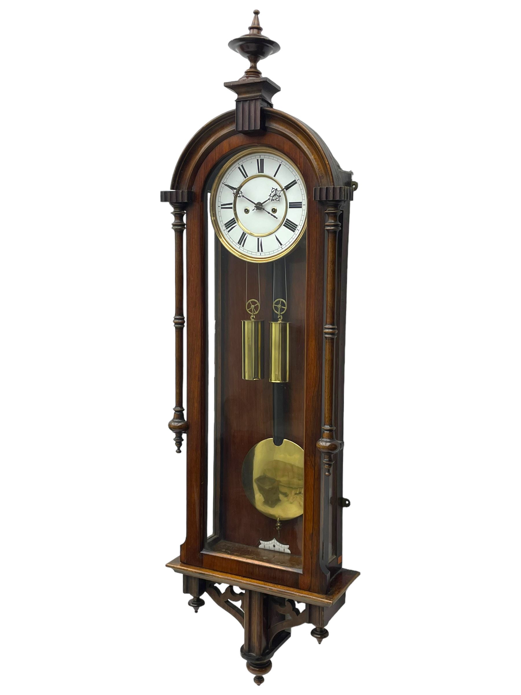 Lenzkirch – 8-day walnut cased weight driven Vienna regulator manufactured 1877-1878, with a break-arch pediment surmounted by a turned finial on a raised cavetto molding, fully glazed arched  door flanked by long ring turned pendants, flat base with open fretwork and two short pendants,  two piece enamel dial within a brass slip, Roman numerals, minute track and pierced steel hands, wooden pendulum with a brass faced bob, two brass cased weights and pulleys, dead beat escapement with a rack striking movement sounding the hours and half hours on a coiled gong, movement serial number 421410. 
Lenzkirch were one of Germanys most highly respected clock manufacturers of the 19th century, founded in the late 1850s the company produced movements and cases of high quality up until 1932.
