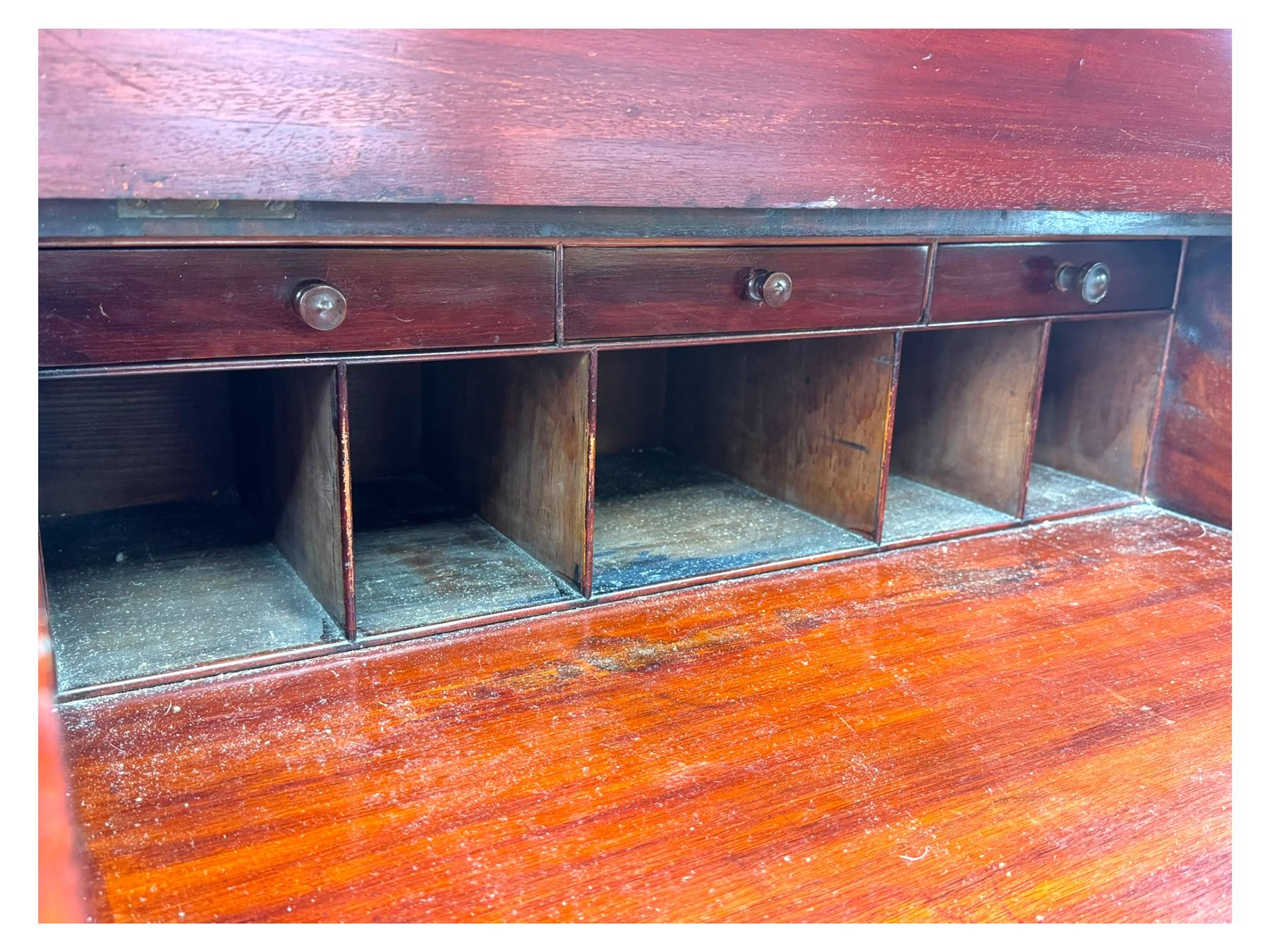Large Victorian mahogany Registry/Dickens’ desk, spindle gallery top, one side with five small drawers and the other with blind cupboard drawer, revealing pigeon holes with scroll carved locking side bars on either side, above a hinged and leathered writing slope with three drawers and pigeon holes underneath, above a central locking drawer with key, the pedestals each with four drawers and  turned knob handles, separates into four parts for transport