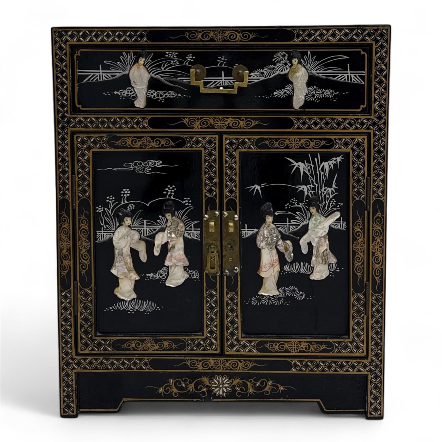 20th century Japanese Shibayama style black lacquered cabinet, rectangular form decorated with mother-of-pearl and hardstone figural inlay, the top with four standing figures, single frieze drawer above two cupboard doors, gilt painted borders and landscape