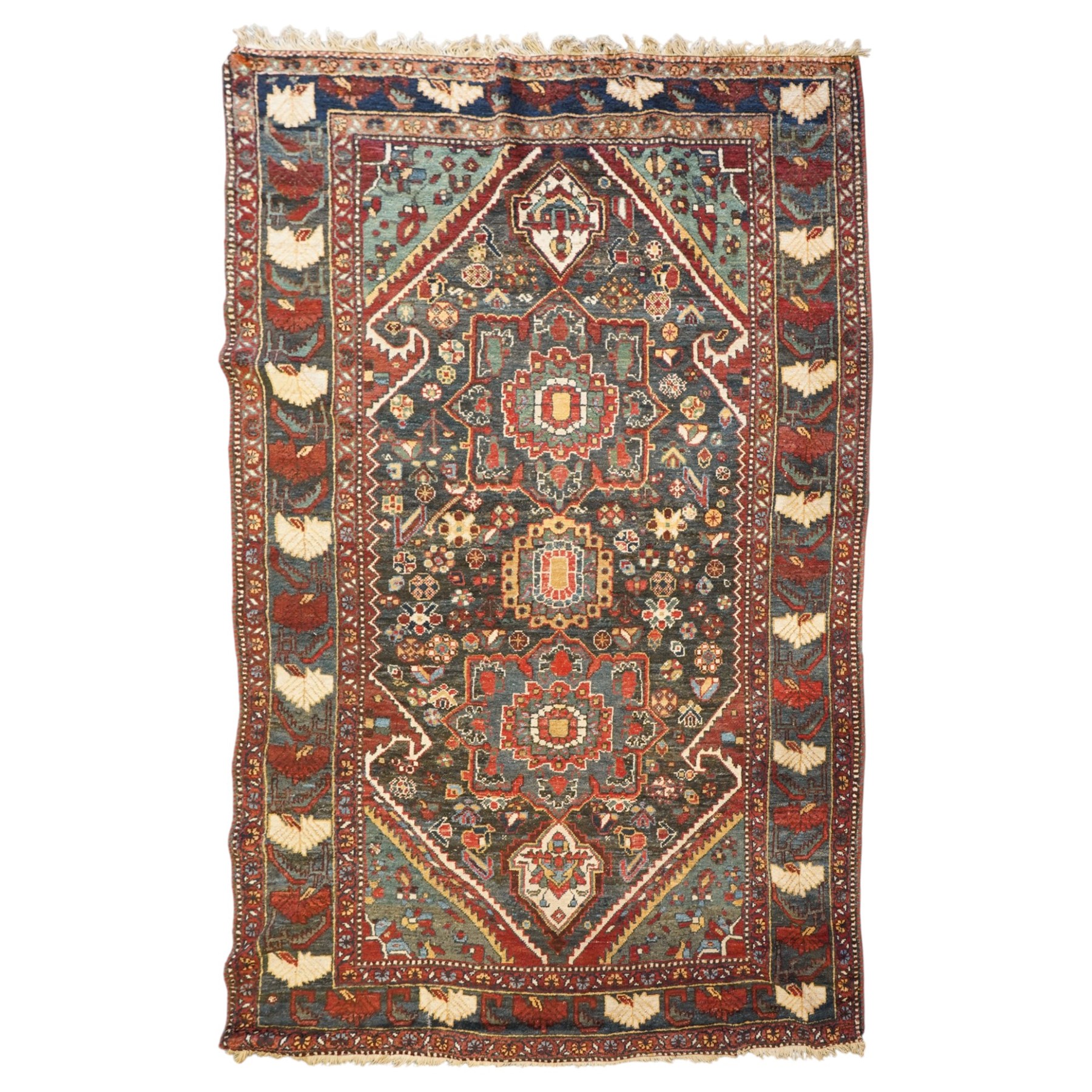 Antique Persian Qashqai dark indigo ground tribal rug, the busy field decorated with a geometric triple pole medallion surrounded by numerous stylised plant motifs with contrasting cyan spandrels, the multiple guard bands woven with stylised palmettes and foliage