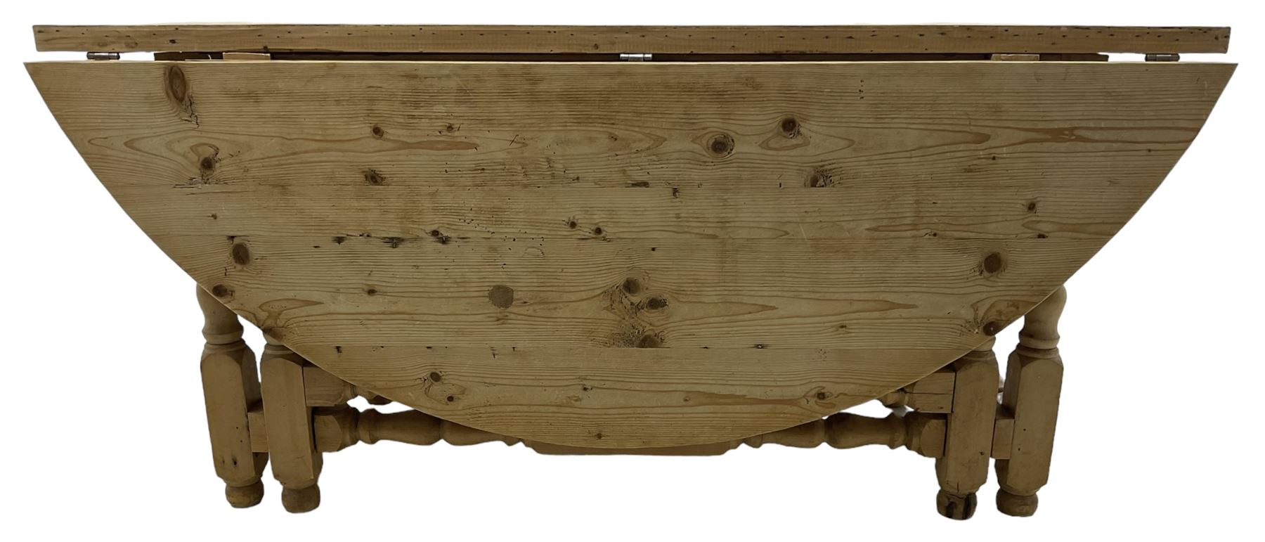 Traditional stripped pine dining table, circular drop-leaf top over double gate-leg action base with turned supports united by turned stretchers