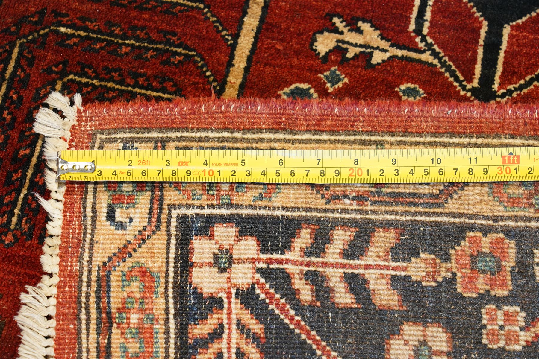 Anatolian crimson ground tribal rug, the field decorated with repeating geometric tree of life motifs with figural designs, the indigo guard band with stylised palmettes