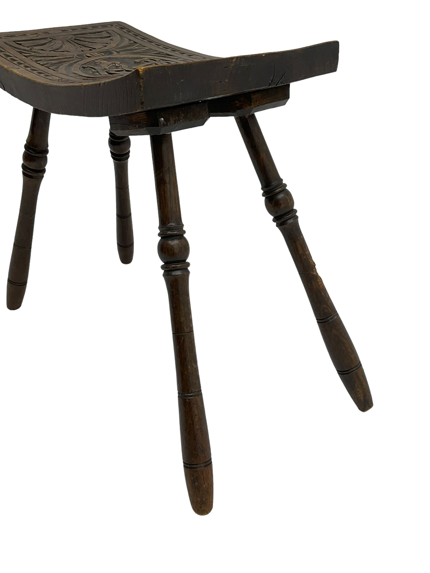 Late 19th century oak stool, rectangular dished top relief carved with floral lunettes and central insignia, on turned splayed supports