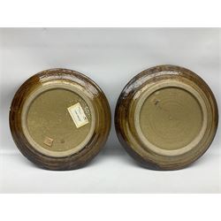 Michael Leach (British 1913-1985) for Yelland pottery; two large glazed stoneware plates with dark brown stylised decoration upon oatmeal ground, together with a jug in merging blue, green and brown, all with impressed marks beneath, largest plate D37cm