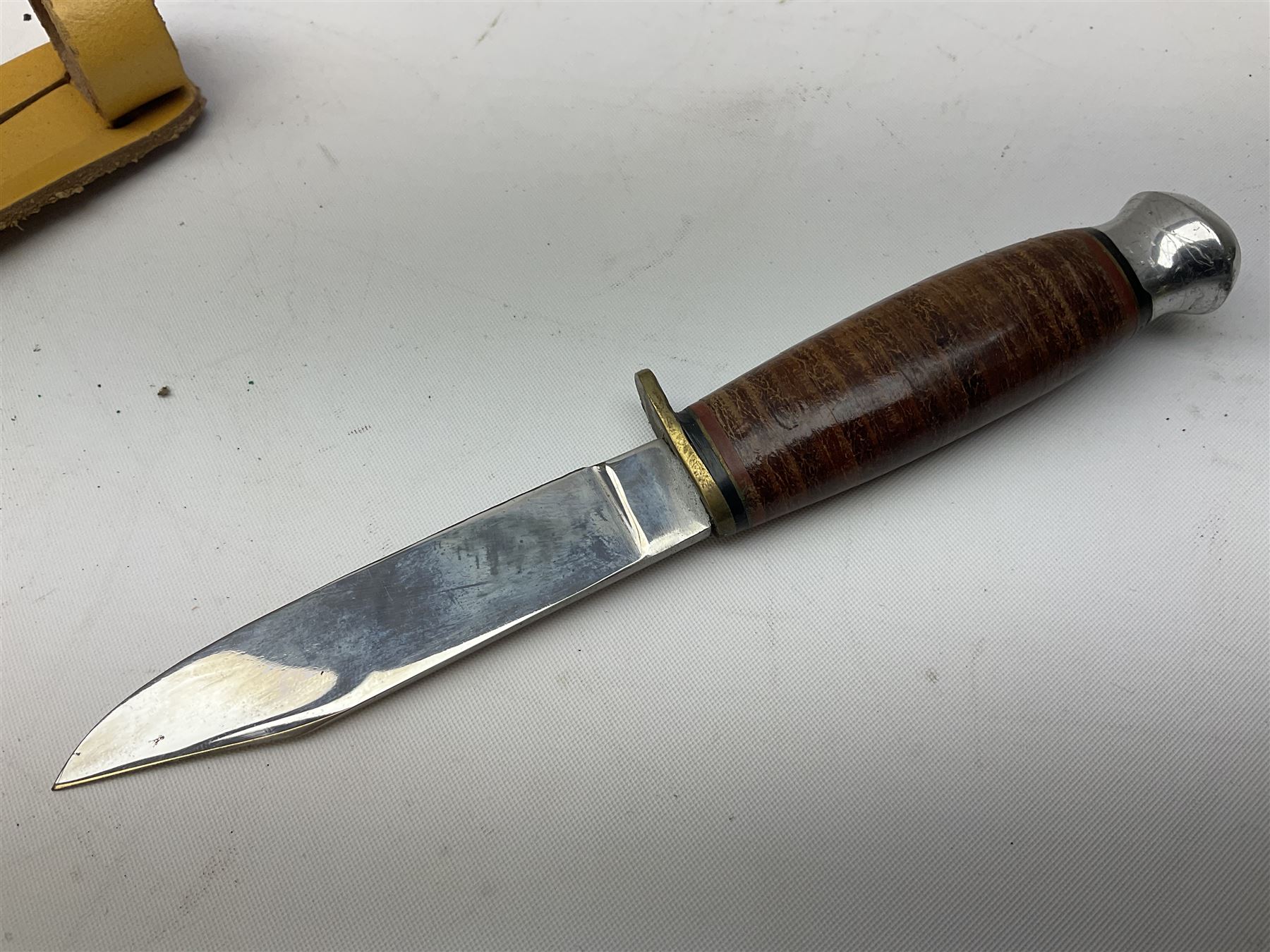 Graduated set of three Bowie knives by J. Nowill & Sons Sheffield England Est. AD1700, each with steel blade, brass cross-piece, stacked leather type grip and alloy pommel; largest blade 13cm and smallest 7.5cm; each in leather sheath (3)