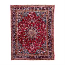 Pair of Persian wool rugs, each with rich red ground, one centred with a diamond-shaped medallion and navy spandrels within a floral field, the other with radiating floral medallion and scrolling foliate motifs, both enclosed by multiple borders with palmette and flowerhead designs, from the region of Kashan 291x376, 299 x 378 