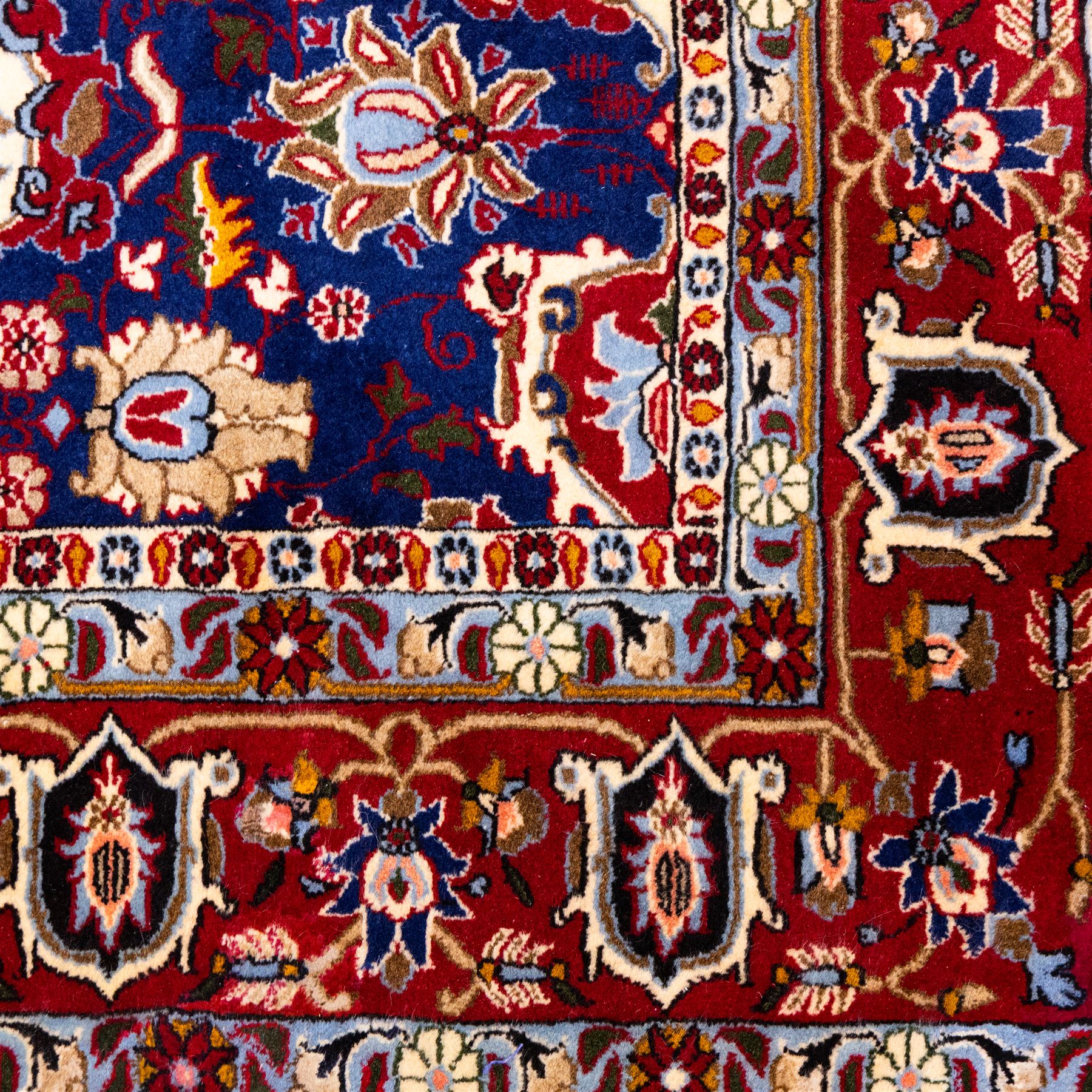 North Central Persian Veramin hand-knotted rug, deep indigo field decorated with an all-over lattice of stylized floral and palmette motifs issuing from an angular vine ornament, enclosed by a broad madder-red border of palmettes and scrolling vine devices between multiple guard stripes, with cotton fringe ends 