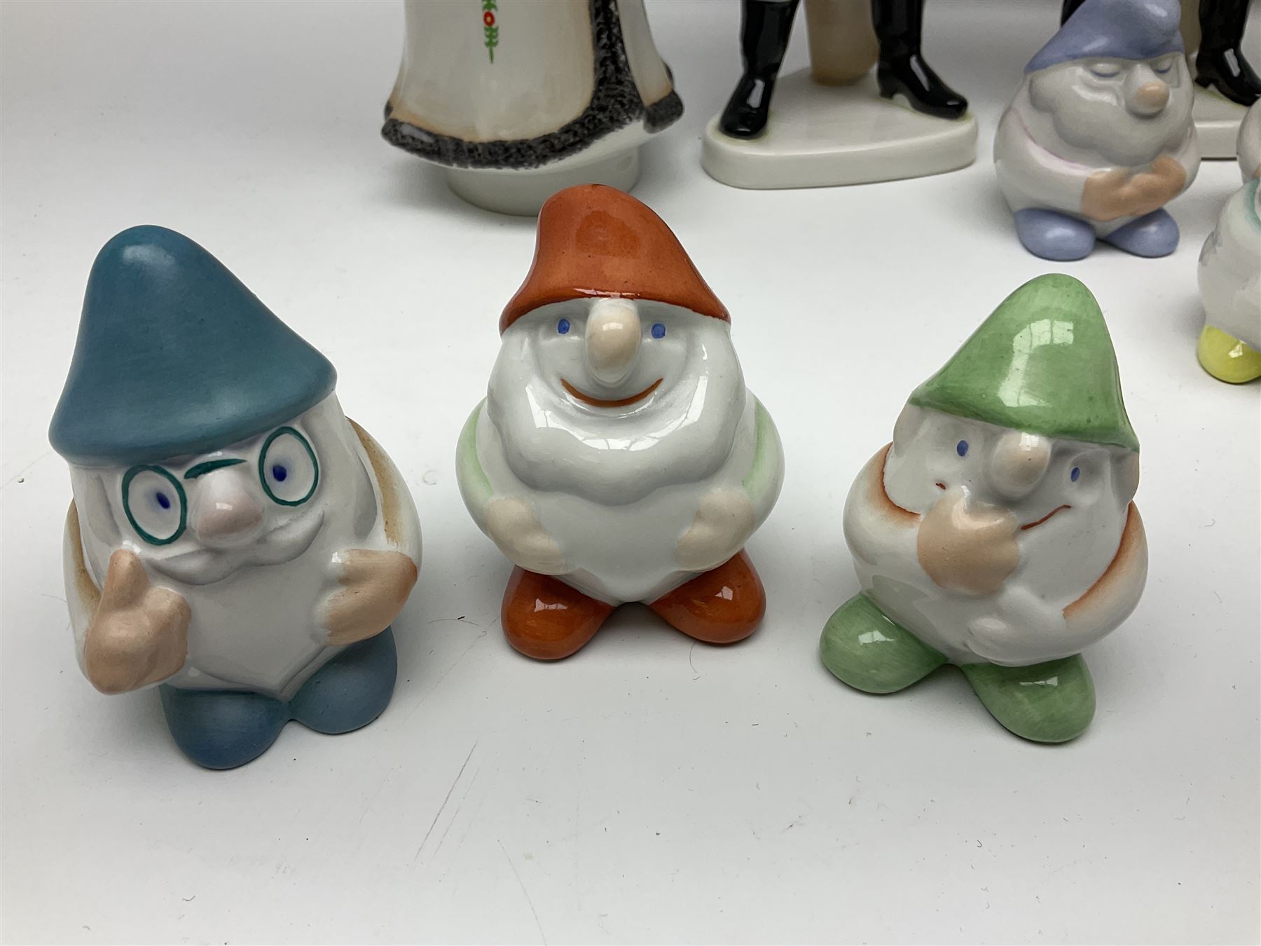 Group of eleven Aquincum of Budapest figures, comprising two of a man in a feather hat, seven dwarves, man and woman in traditional dress, all with printed marks beneath