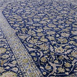 Central Persian Kashan hand-knotted rug, deep blue all-over field, finely decorated with dense scrolling floral sprays, palmettes, and flowering vines in ivory, soft gold, and pale green tones, enclosed by a multi-band floral border with corresponding guard stripes, with cotton fringe ends, signed Shah Abassi Workshop 