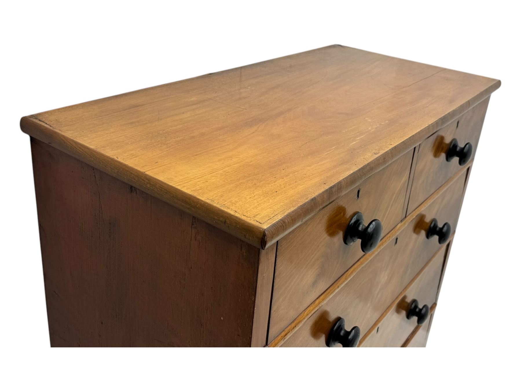 Late Victorian mahogany chest of drawers, with rectangular top over two short and three long graduated drawers, each fitted with ebonised turned knob handles and keyholes, raised on turned supports