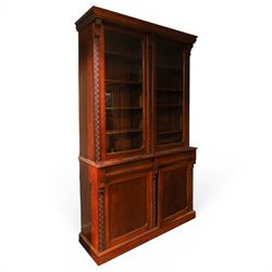 Victorian carved mahogany enclosed bookcase on cupboard, projecting moulded cornice over t...