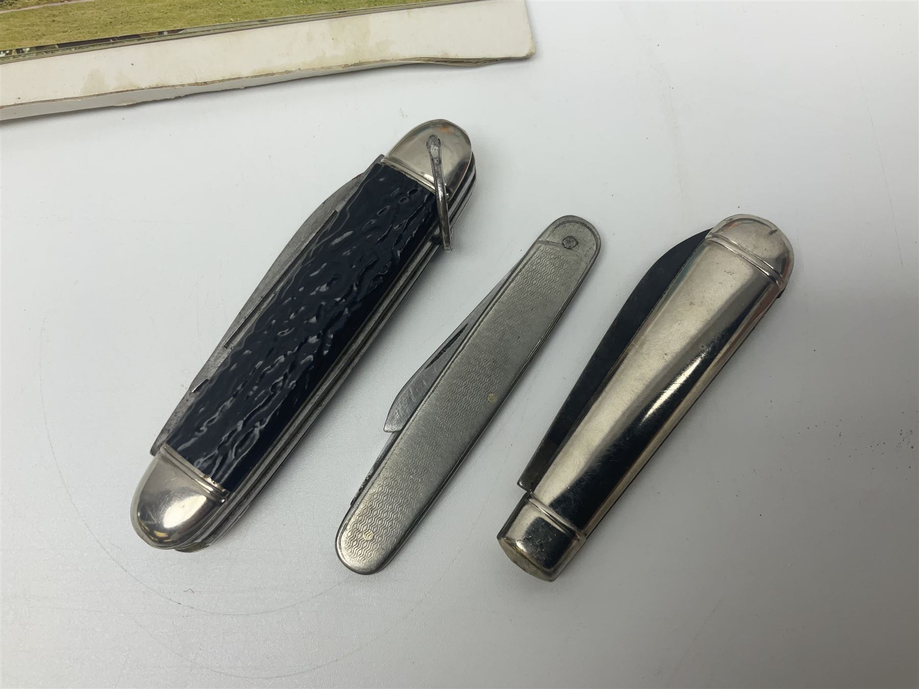 Seven pen knives, two lighters, including one Ronson example and a collection of postcards