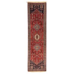 Persian Qashqai crimson ground runner, the central field decorated with three large geometric medallions with intricate angular and floral motifs, the indigo spandrels with complementary geometric designs, bordered by an ivory band with repeating floral patterns and angular vines