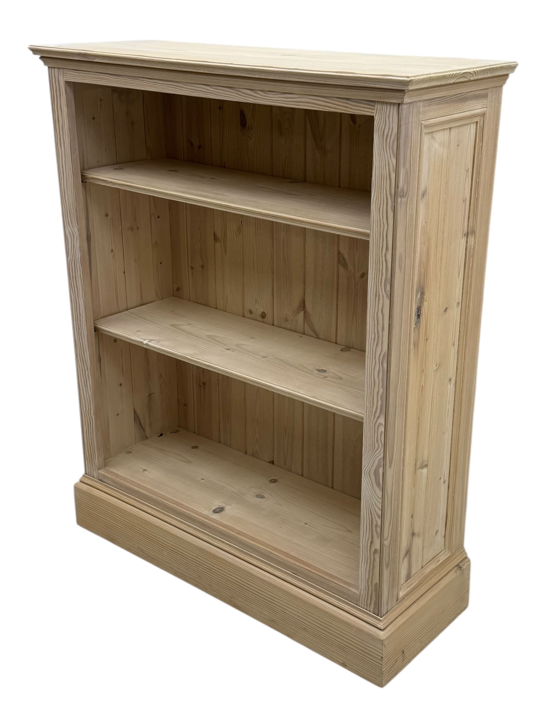 Contemporary light pine open bookcase, rectangular top with stepped moulded edge above a boarded back, fitted with two adjustable shelves, on a plinth base