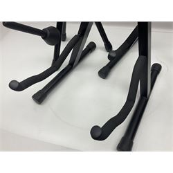 Four folding tubular guitar stands, two by RockJam; and folding tubular saxophone stand (5)