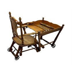 Late 19th century American oak child's metamorphic high chair and play table, carved spindle backrest with pierced splat, detachable tray with abacus and hand painted pastoral decoration, on turned supports with metal wheels