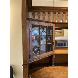 Shapland and Petter - Arts & Crafts period oak dresser, raised gallery top with spade balustrade, central bevelled mirror flanked by two cabinet, astragal glazed doors with yellow tinted glass and bullseye panes, the sides with pierced heart shaped decoration, fitted with two drawers and two double cupboards, enclosed by linenfold panelled doors,  copper work strap hinges and fixtures, on shaped spade feet, the locks stamped 'S&P'