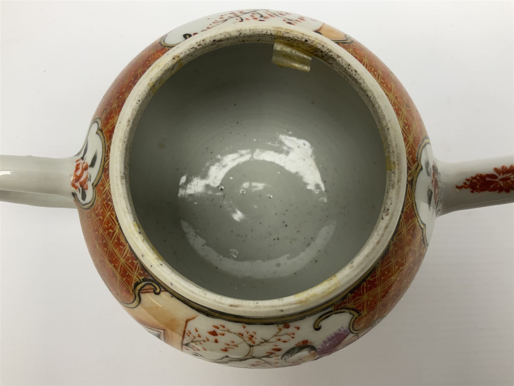 Two late 18th/early 19th century Chinese export teapots, the largest example of globular form with curved handle and straight spout, decorated in the Mandarin style with figural scenes surrounded by red scale reserves, H13.5cm, the second smaller example decorated in underglaze blue with two musicians in a landscape set with willow tree and fence, H10.5cm

