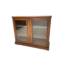 Victorian bookcase, rectangular top over two glazed doors enclosing two shelves, on skirted base