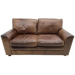 Two-seat sofa, traditional shape with rolled arms, upholstered in distressed brown leather, on turned feet; together with small footstool