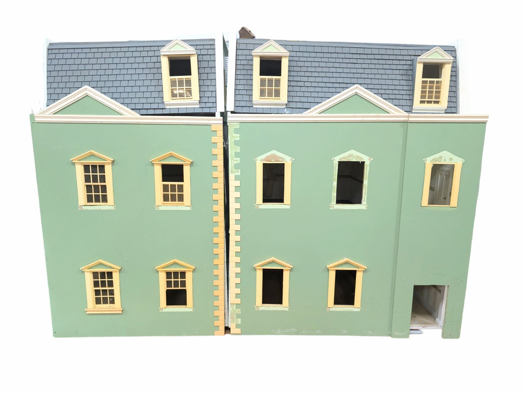 Two modern three storey dolls houses, each painted green with decorated interiors, both upon a single white wooden base, together with a large collection of dolls house furniture, accessories and figures 
