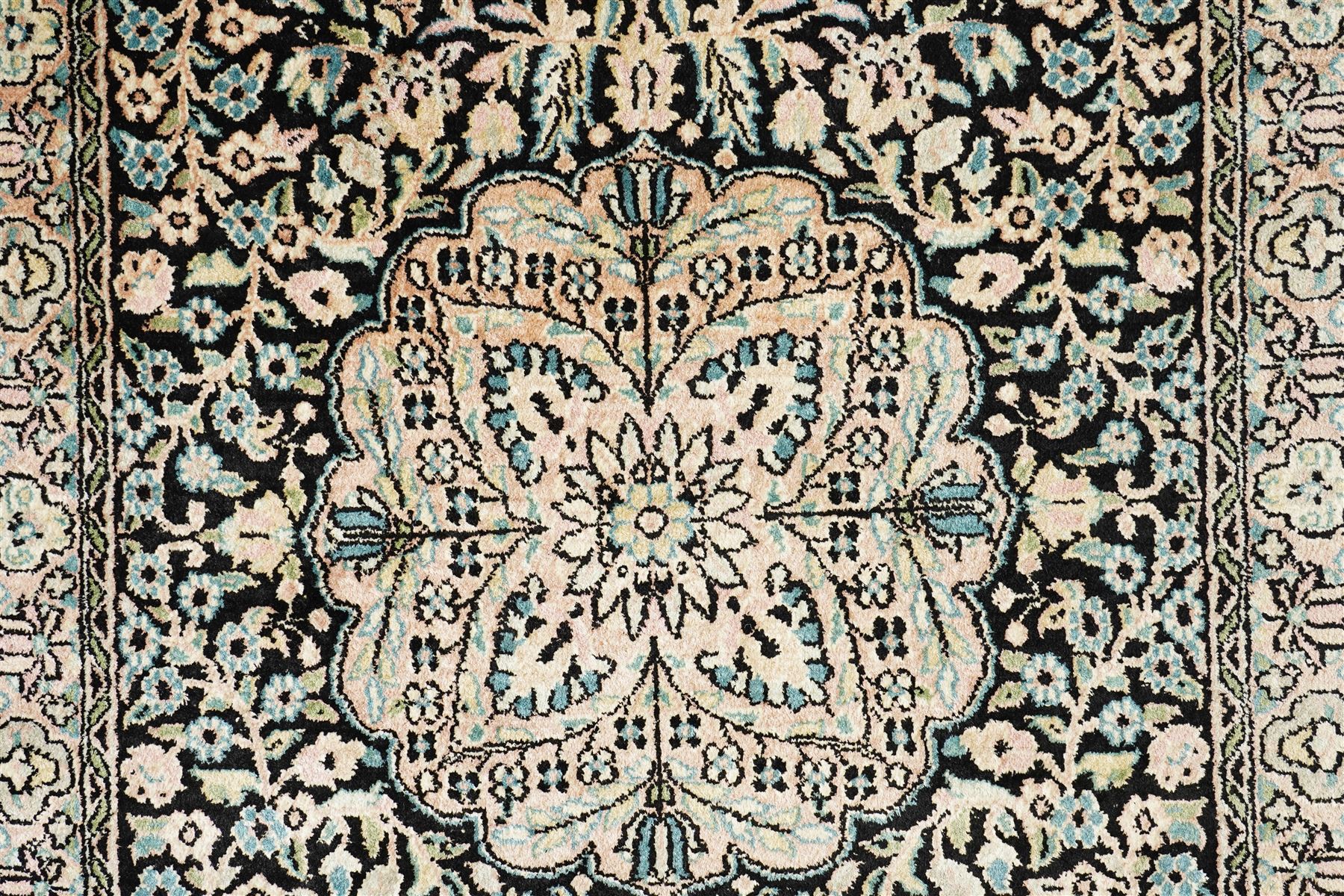 Persian style rug, central floral medallion surrounded by intricate palmetters, vines and rosettes, navy blue ground with ivory and pink highlights