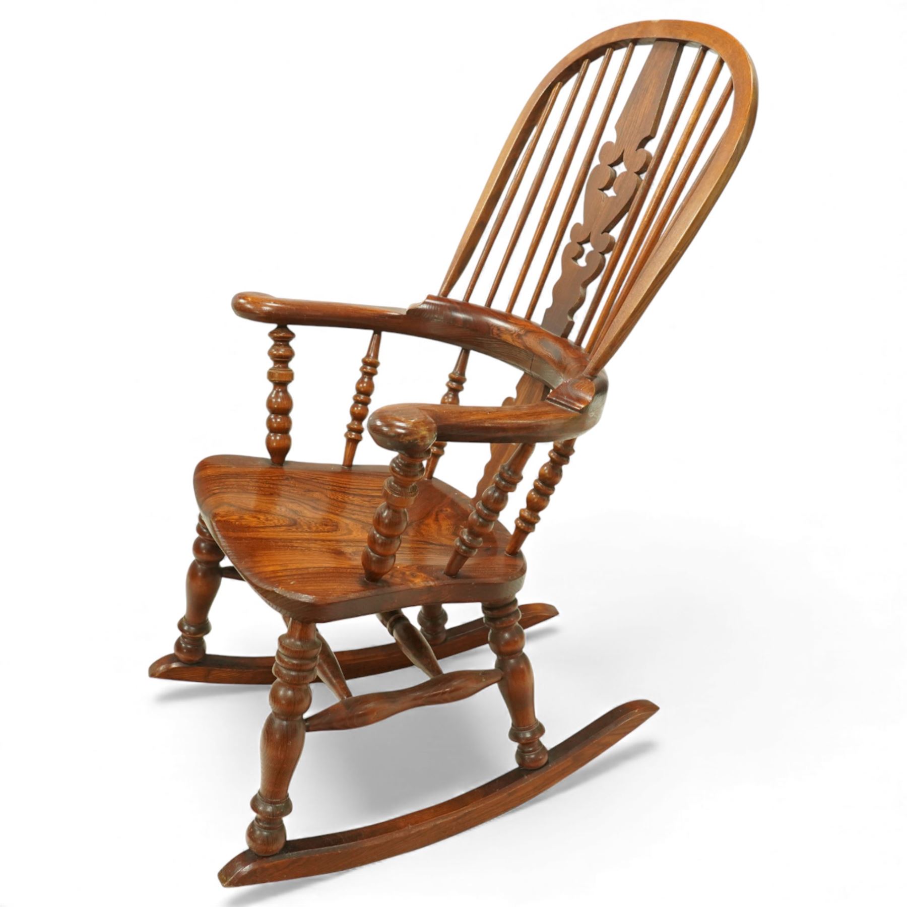 Broadarm Windsor rocking chair, arched crest rail enclosing turned spindle back with pierced splat, wide shaped arms with turned supports, solid elm seat, raised on turned legs united by double stretchers, on swept rockers