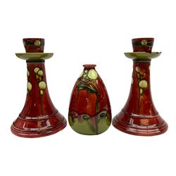 Minton Secessionist vase, with tube-lined stylised flower head decoration upon a red and green ground, printed mark to base 'Minton Ltd, No. 31', together with a matching pair of Minton Secessionist candle sticks, candlestick H17cm