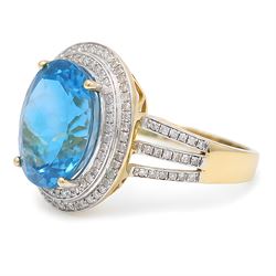 14ct gold Swiss blue topaz and diamond cluster ring, single oval cut topaz of approx 8.85 carat, surrounded by two rows of single cut diamonds and split diamond set shoulders