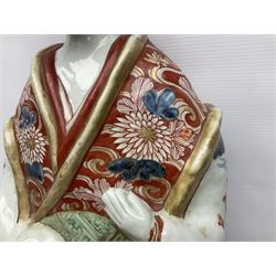 Large Japanese Imari porcelain figure, modelled as a Bijin, wearing a long kimono decorated with apple blossom and leafy branches on a white ground, with gilt detailing, possibly Edo period, H63cm