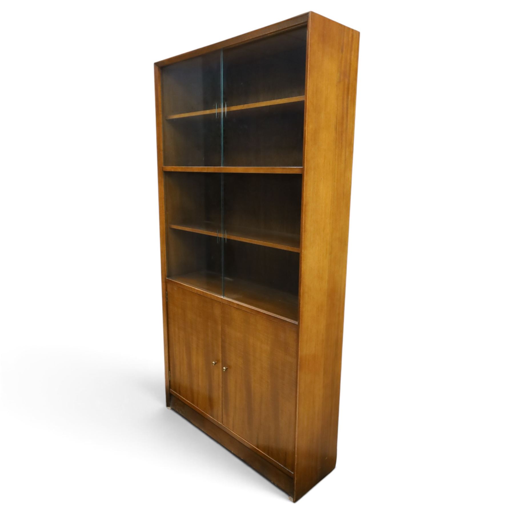 Herbert E Gibbs - Mid 20th century teak glazed bookcase cabinet, rectangular form with two sliding glazed doors enclosing adjustable shelves, lower cupboard enclosed by twin doors and fitted with internal shelf, on plinth base