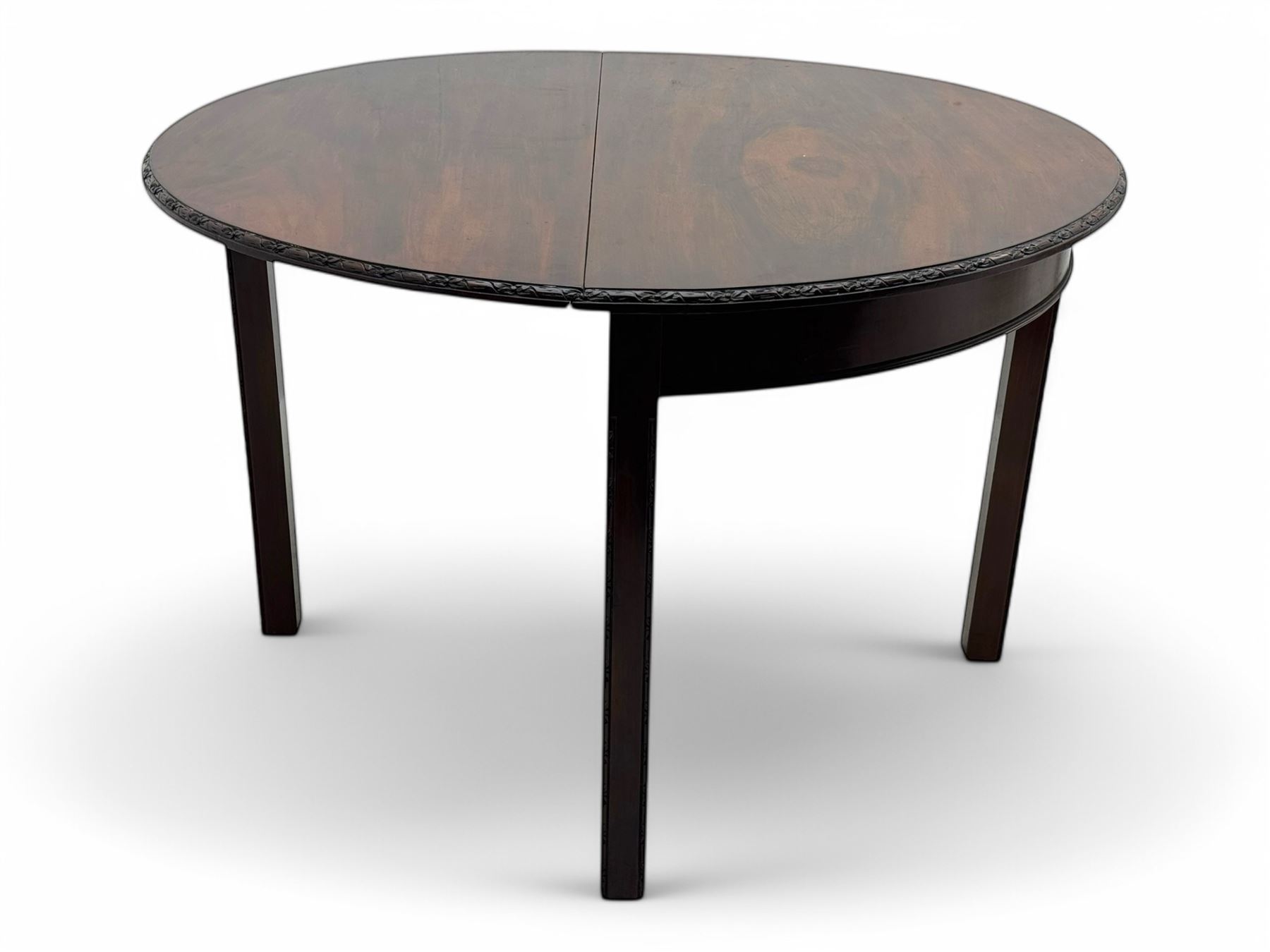 Early 20th century mahogany demi-lune table, the circular top with carved foliate border, raised on square section supports with relief carved edges