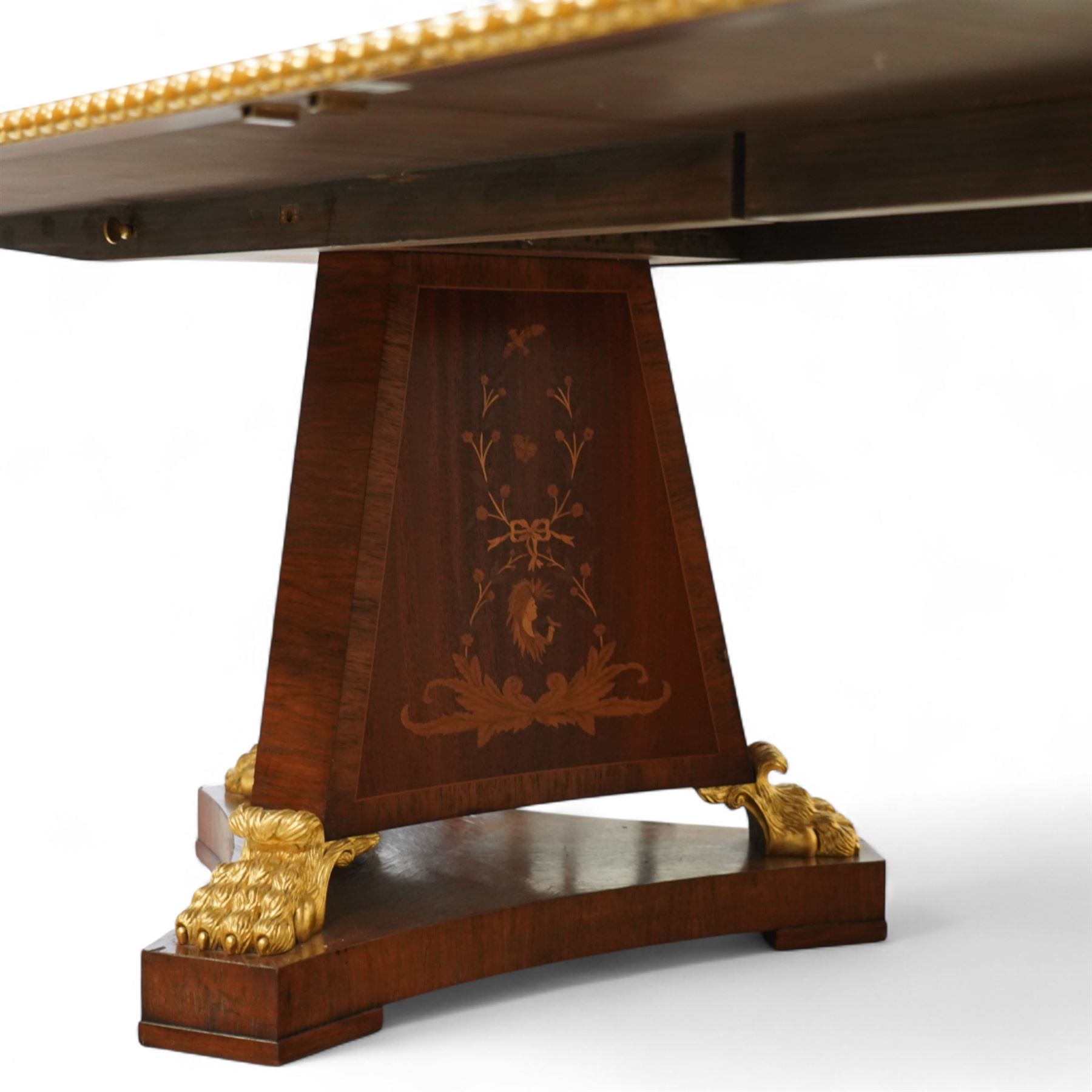 Arthur Brett & Sons - late 20th century twin pedestal dining table in the Second Empire style, the oval Amboyna burl veneered top, bordered with tulipwood crossbanding and delicate floral marquetry inlay, and rosewood crossbanded outer border within gilt gadrooned edge, over two mahogany triform pedestal bases with rosewood crossbanding and decorated with neoclassical marquetry of tied ribbons, leafy sprays, and scrolling acanthus decoration, raised on carved and gilded lion paw terminals on plinth bases, underside with maker's label