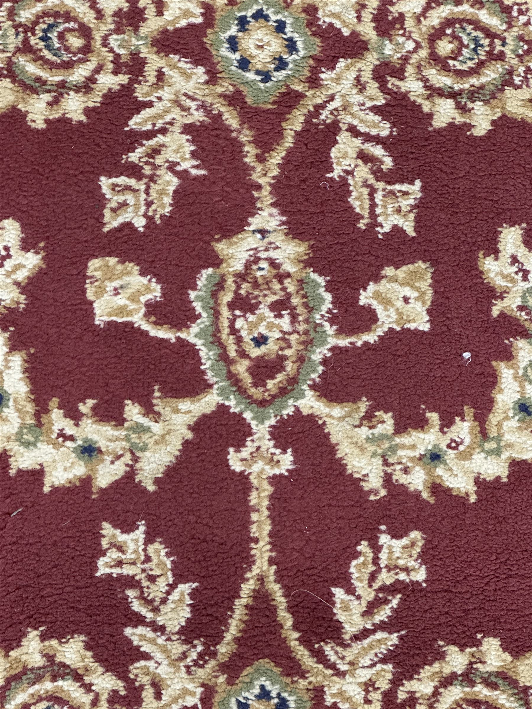 Contemporary Dunelm 'Legacy' ground rug, the field decorated with symmetrical scrolling foliate and floral motifs, bordered by an ivory band with repeating floral designs interspersed with leafy branches, inner guard stripe with fine linear patterning